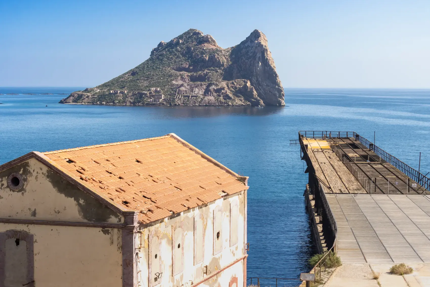 Vía Verde del Embarcadero del Hornillo en Águilas: pasarela peatonal y cargadero metálico de mineral de hierro proyectándose sobre la bahía del Mediterráneo, con la Isla del Fraile al fondo.