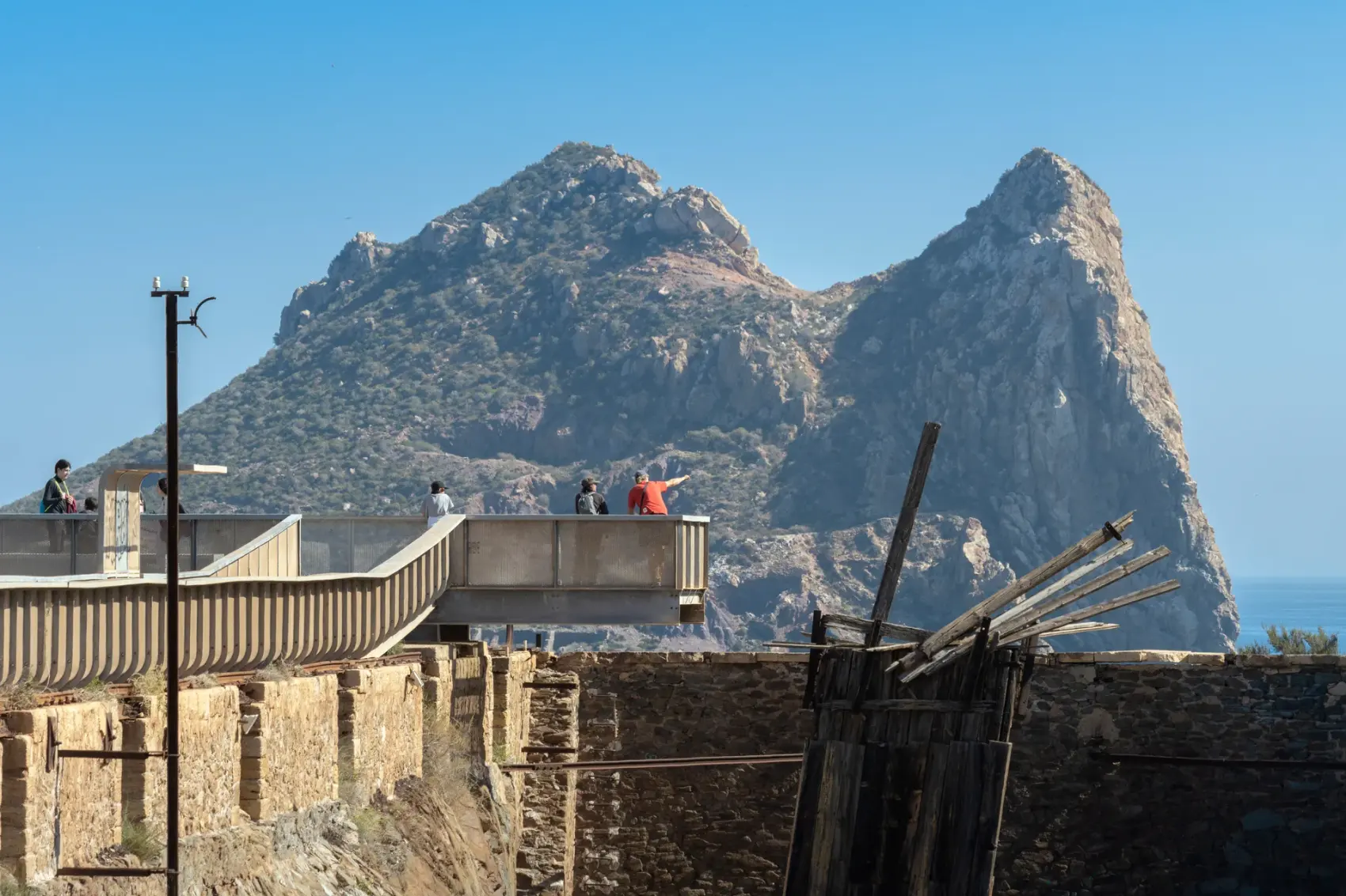 Vía Verde del Embarcadero del Hornillo en Águilas: pasarela peatonal y cargadero metálico de mineral de hierro proyectándose sobre la bahía del Mediterráneo, con la Isla del Fraile al fondo.