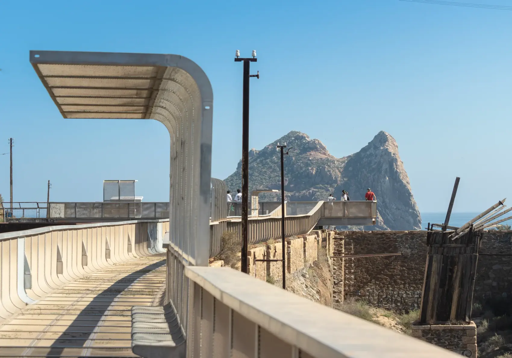 Vía Verde del Embarcadero del Hornillo en Águilas: pasarela peatonal y cargadero metálico de mineral de hierro proyectándose sobre la bahía del Mediterráneo, con la Isla del Fraile al fondo.