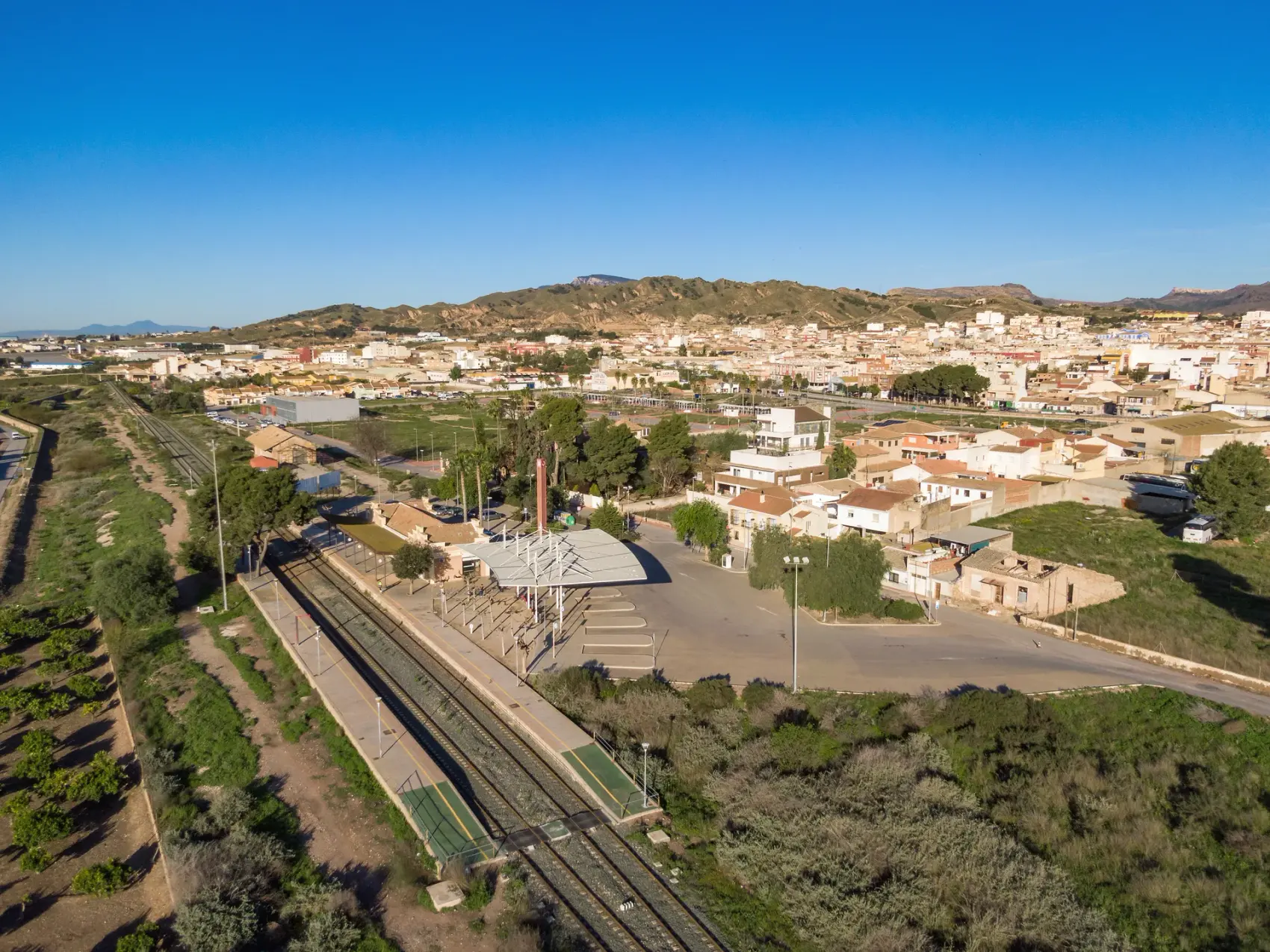 Puente de fábrica sobre el cauce del río Guadalentín, principal obra del antiguo trazado ferroviario Totana-Cartagena, visto entre los frutales del Campo de Cartagena bajo cielo despejado