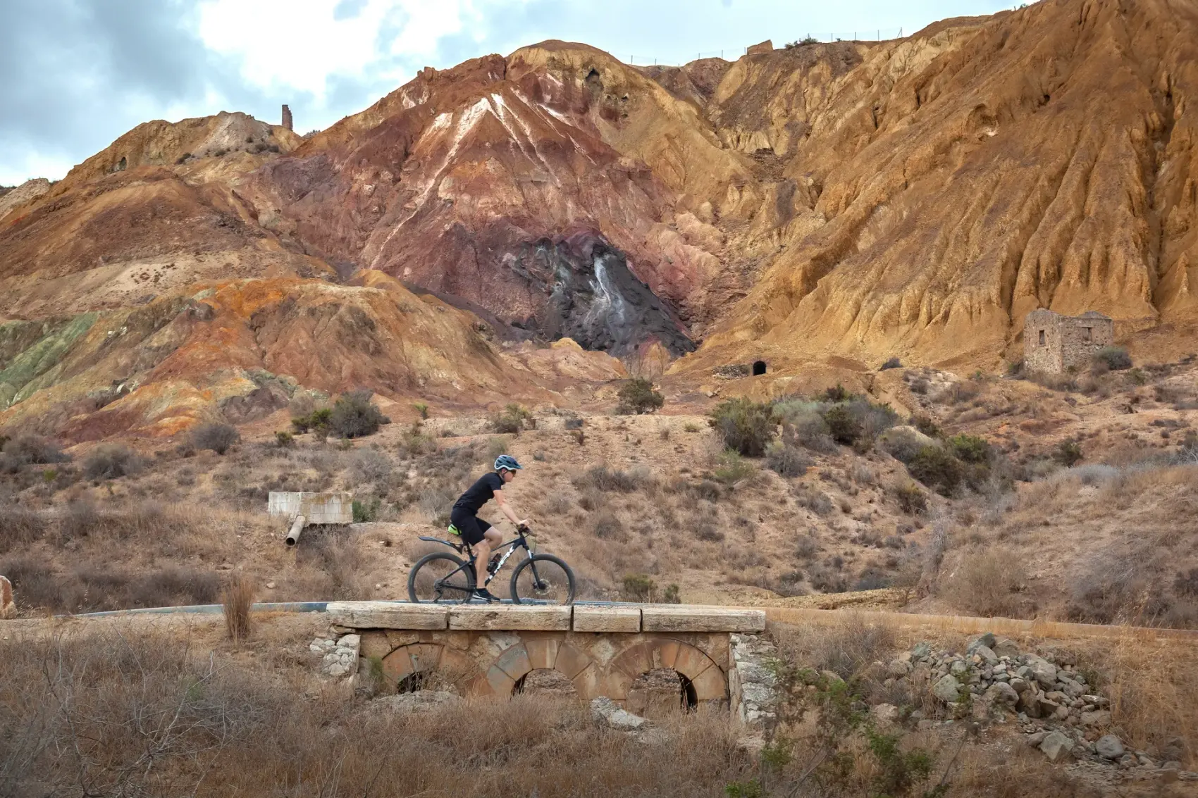 Camino de tierra compactada de la Vía Verde de Mazarrón descendiendo entre los cabezos ocres y rojizos del antiguo Coto Minero de San Cristóbal bajo un cielo azul