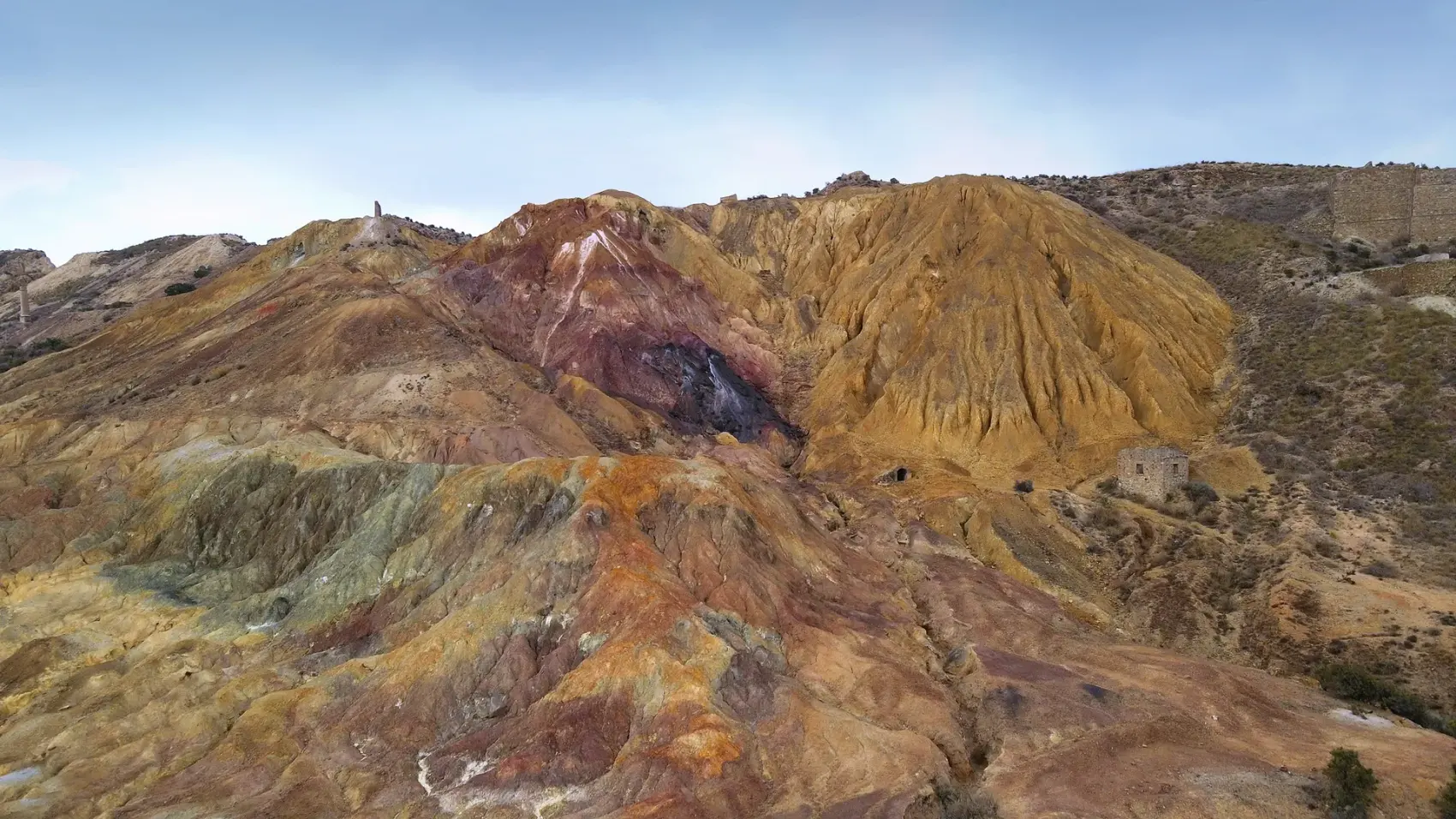 Camino de tierra compactada de la Vía Verde de Mazarrón descendiendo entre los cabezos ocres y rojizos del antiguo Coto Minero de San Cristóbal bajo un cielo azul